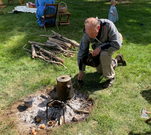 Jeff Houston crouches by a fire to get himself a cup of coffee on the morning of May 27 at the Century Village Museum Civil War Encampment. Houston, who lives in Wadsworth, is a member of a Confederate Army re-enactment unit that is participating in the event. The encampment wraps up May 28 with activities from 10 a.m. to 5 p.m. at Century Village Museum, located at 14653 E. Park St. in Burton Village. (Bill DeBus - The News-Herald)